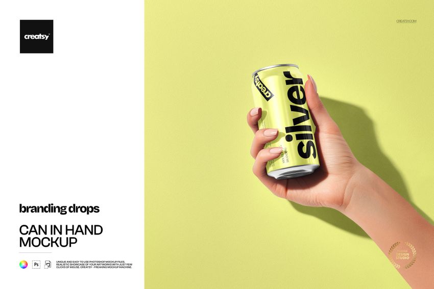 Hand holding a silver can with bold black text on a light yellow background, front view, drinkware mockup.