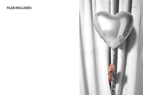 Hand holding a silver heart-shaped balloon in front of white velvet curtains, party supplies PSD mockup scene.