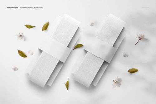Mockup showing two plain white fabric ribbons on paddles, surrounded by scattered leaves and delicate flower petals.