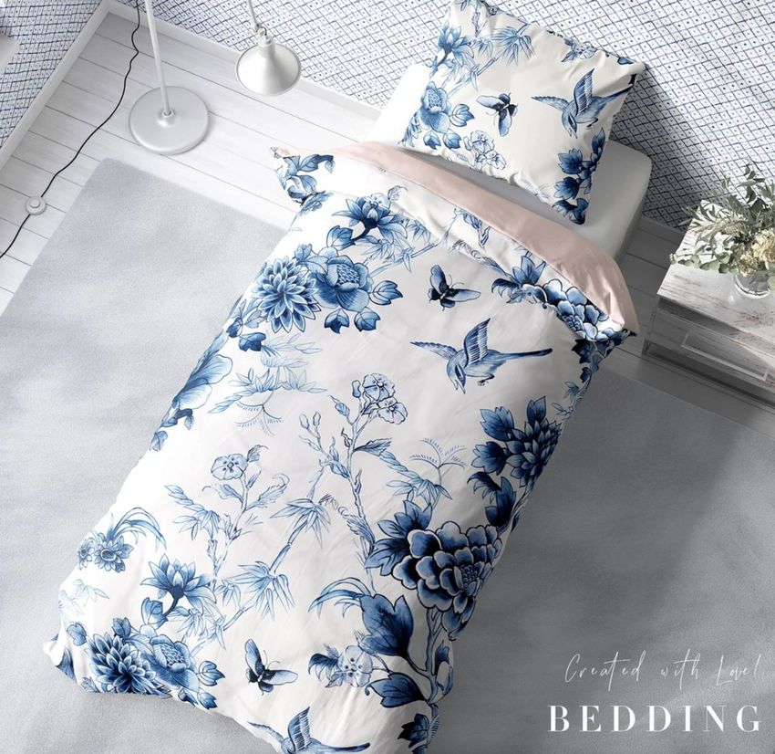 Single bed bedding mockup featuring a white duvet and pillow with blue floral and bird patterns, viewed from above in a bright room.