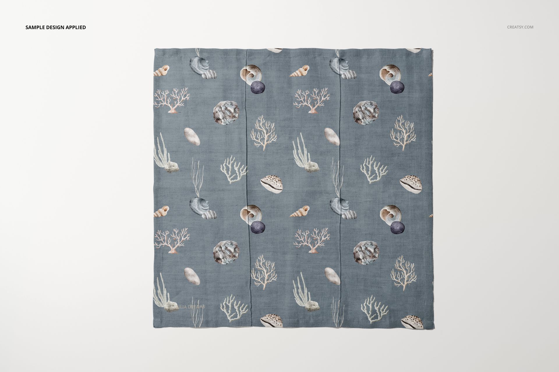 Square cotton linen napkin mockup with a blue background and sea-inspired pattern, shown from a top view on a white surface.