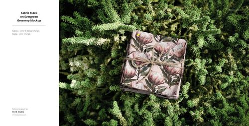 PSD mockup showing a stack of decorative fabric on vibrant outdoor plants, photographed from a top-down angle.