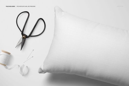 Rectangular white pillow mockup shown from above, with sewing tools including scissors, spool, and ribbon on the side.