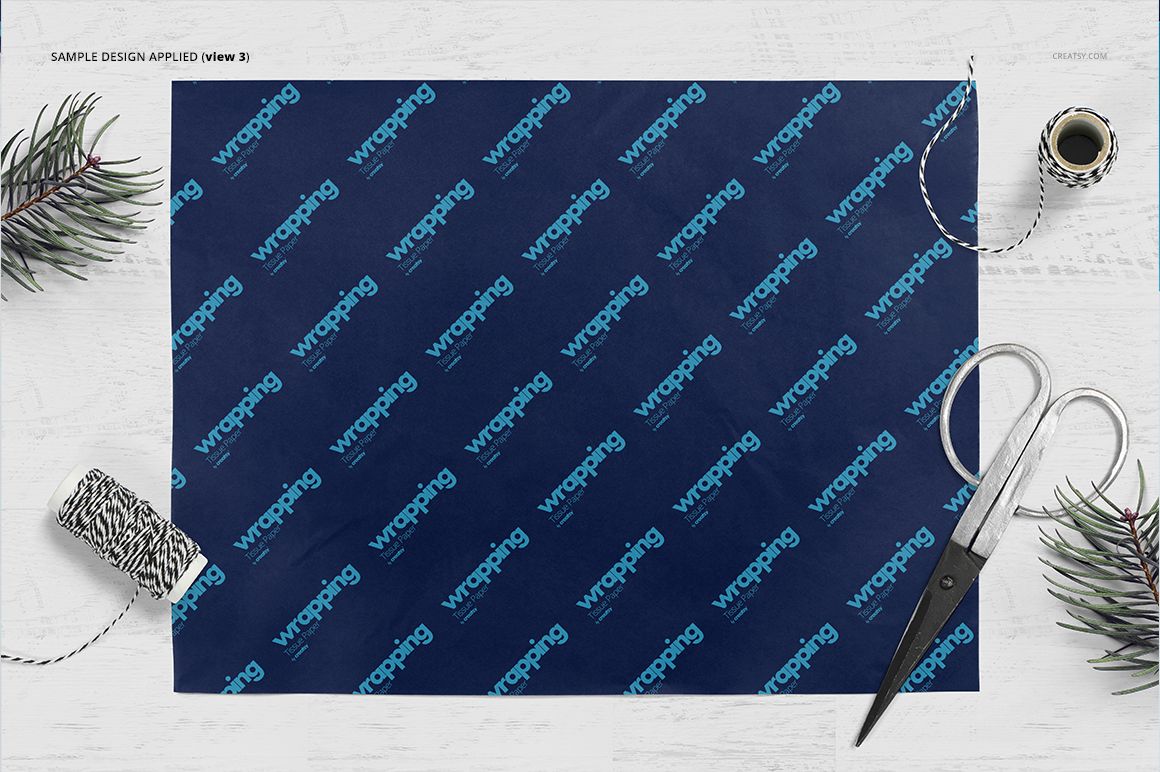 Wrapping tissue paper mockup with a dark blue sheet featuring a repeating text pattern, shown from a top view on a white surface.
