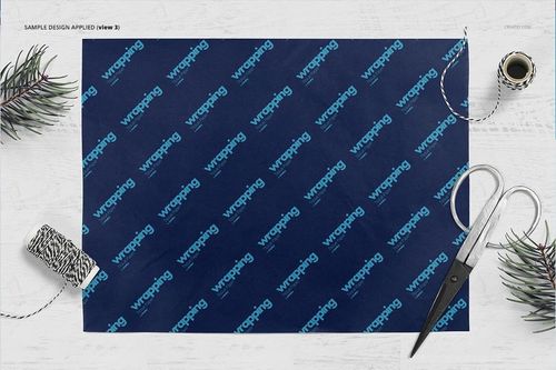 Wrapping tissue paper mockup with a dark blue sheet featuring a repeating text pattern, shown from a top view on a white surface.
