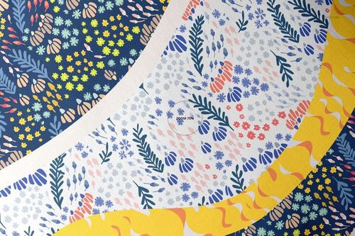 Top view of a throw pillow mockup featuring curved fabric sections with floral and leaf patterns in blue, yellow, and pink.