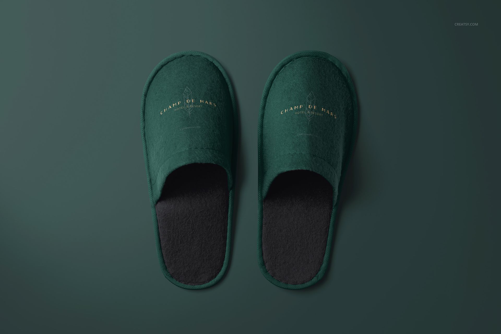 Mockup of green hotel slippers with gold branding, displayed flat against a solid green backdrop from a bird's-eye perspective.