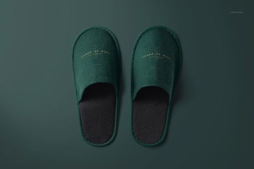 Mockup of green hotel slippers with gold branding, displayed flat against a solid green backdrop from a bird's-eye perspective.