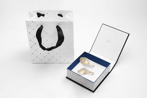 Open jewelry box mockup with blue lining and two decorative fish pieces, placed beside a white patterned gift bag.