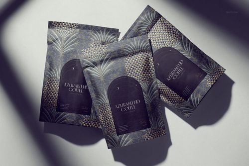 PSD mockup of coffee packaging with elegant leaf and geometric motifs in dark tones, viewed from above with shadows.