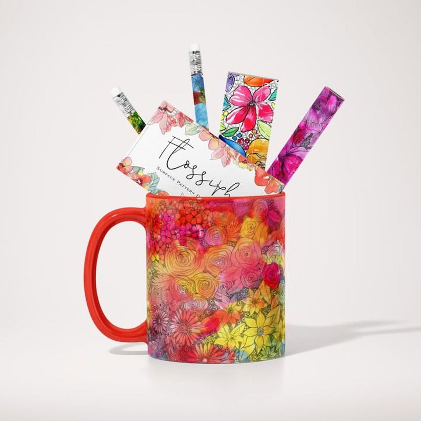 Mug mockup featuring a colorful floral pattern, filled with stationery items such as pencils, cards, and bookmarks on a light background.