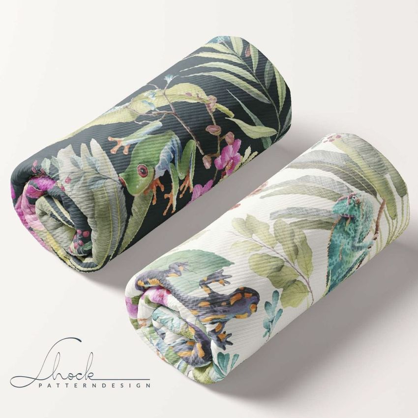 Two rolled fabric mockups with tropical leaf and frog patterns, one on a dark background and one on a light background, placed on a plain surface.