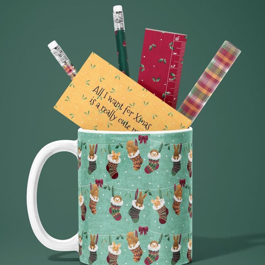 Mug mockup featuring a festive animal pattern, filled with office supplies like pencils, a ruler, and patterned paper on a green background.