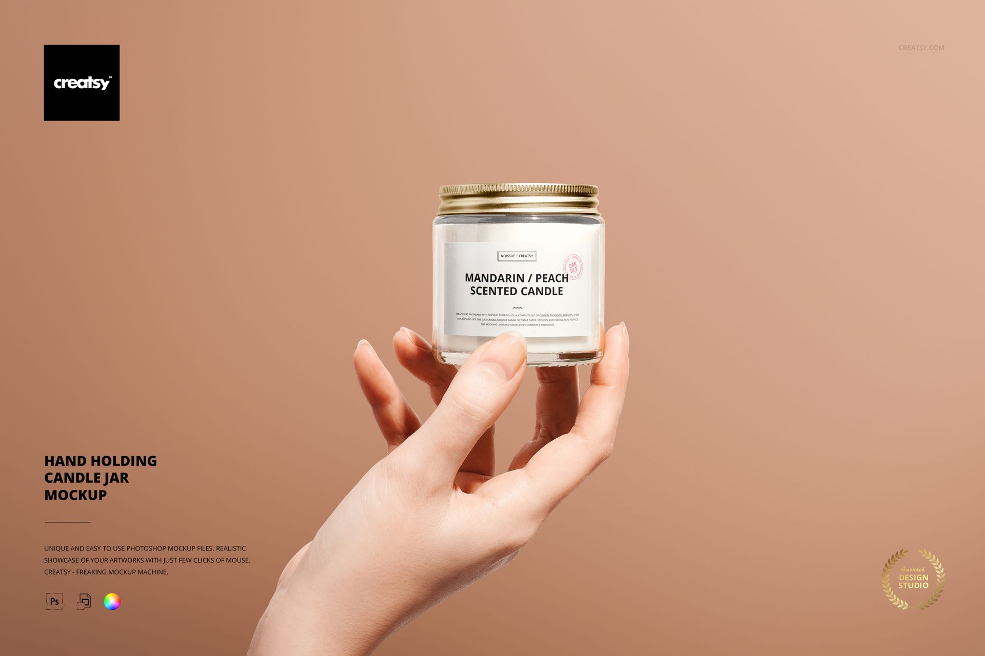 Hand holding a round glass candle jar with gold lid against a solid beige background, front view mockup scene.