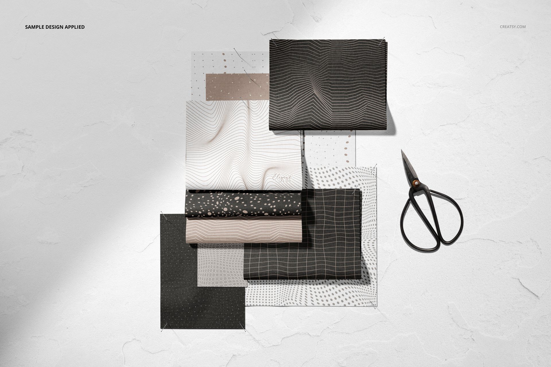 Fabric mockup set featuring rectangular textile samples with grid and wave designs, scissors placed nearby.