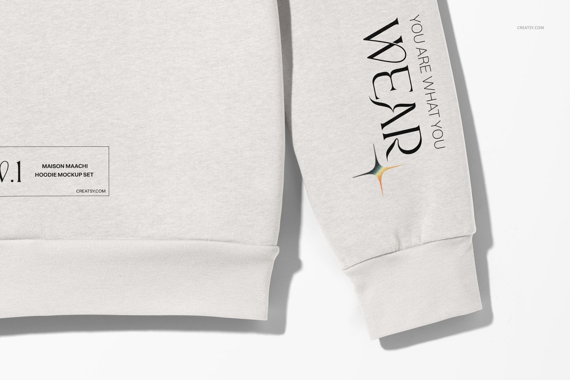 Oversized hoodie mockup in light gray fabric, close-up front view showing sleeve text and hem label details.