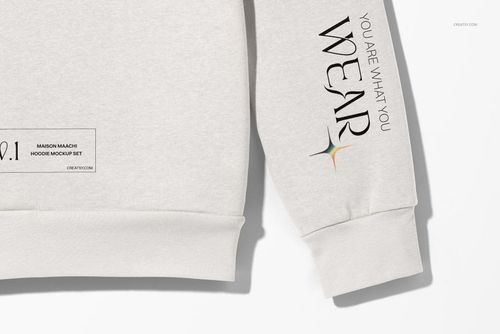 Oversized hoodie mockup in light gray fabric, close-up front view showing sleeve text and hem label details.