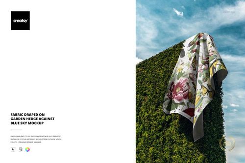 PSD mockup of a fabric with vibrant flower design displayed on a garden hedge, set against a bright blue sky.