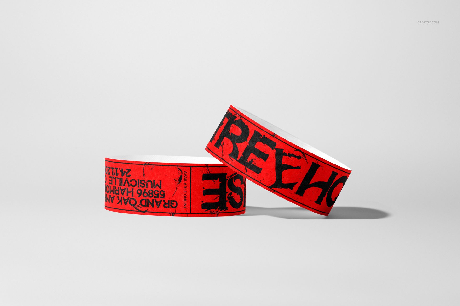 PSD mockup of red paper wristbands with black graphic text, arranged on a simple gray surface in a studio setting.