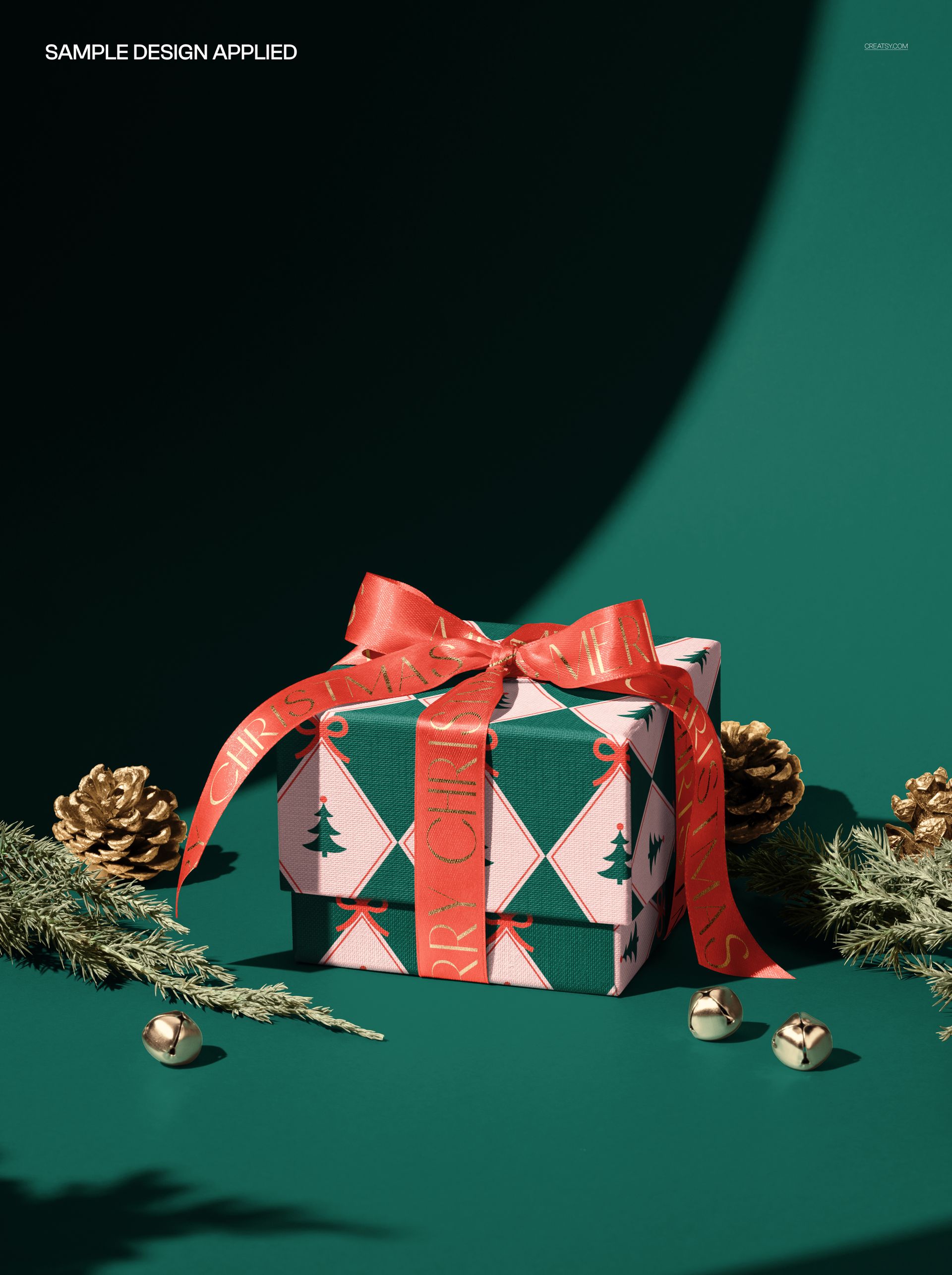 Christmas gift box mockup with red ribbon, pine cones, fir branches, and gold bells on a green background.