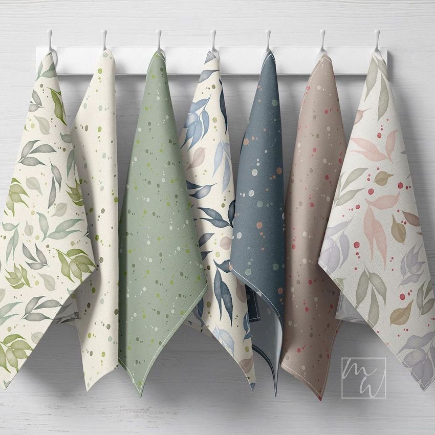 Hanging tea towels mockup showing six towels with botanical and dotted patterns in pastel green, blue, beige, and pink tones.