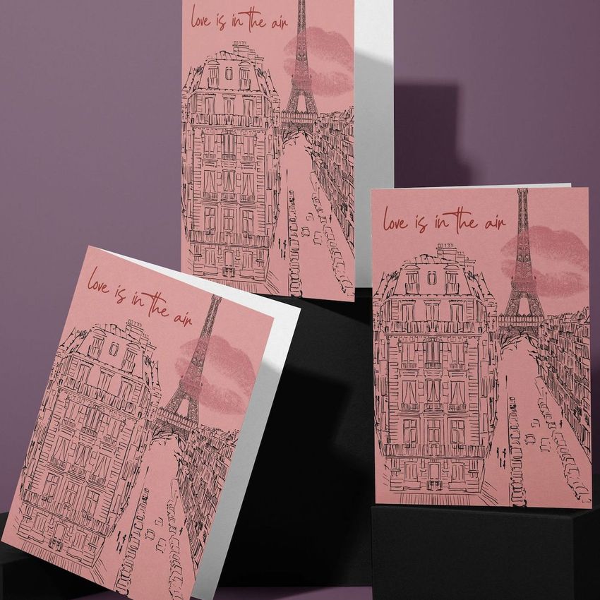Greeting card mockup set showing three pink cards with illustrated Paris buildings and the Eiffel Tower on a mauve background.