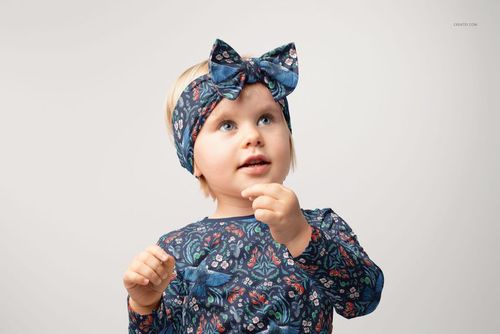 Kids PSD mockup showing adjustable bow tie style headband in blue with floral pattern, front perspective.