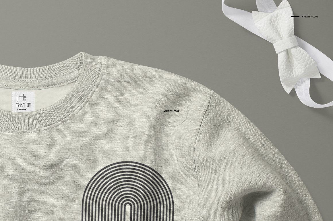 Heather gray baby sweatshirt mockup shown from a top angle, featuring a black geometric print and a white bow nearby.