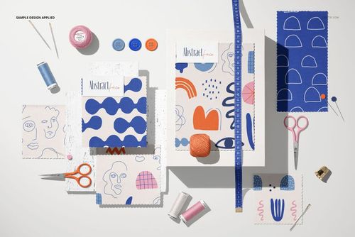 Jersey fabric swatches featuring abstract blue and orange patterns displayed flat with sewing tools and accessories.