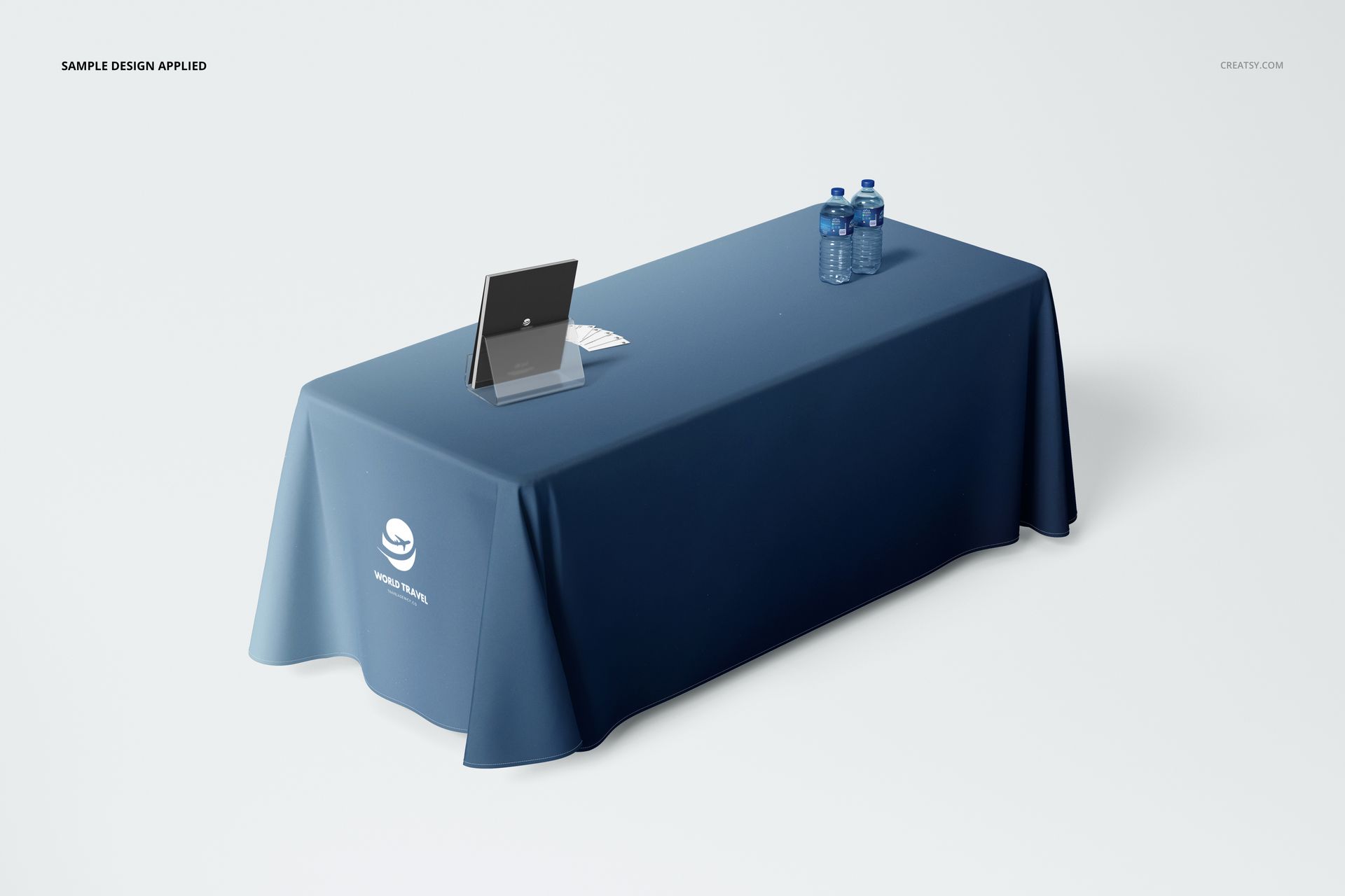 Front view of a blue polyester tablecloth mockup draped over a table, featuring a subtle white emblem and office props.
