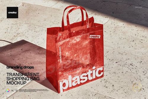 Transparent shopping bag with red handles and trim displayed on a stone floor, shown in a front angle PSD mockup.