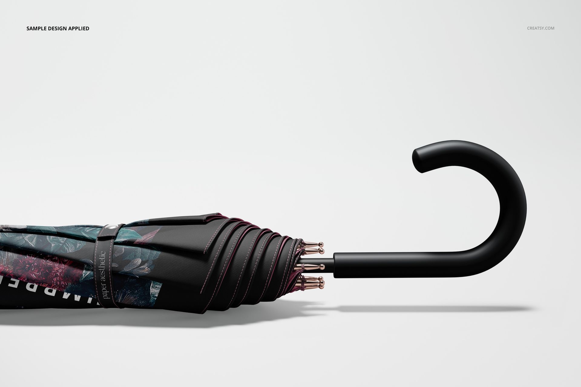 Closed umbrella mockup with a black curved handle, featuring a dark floral pattern, shown from a side view.