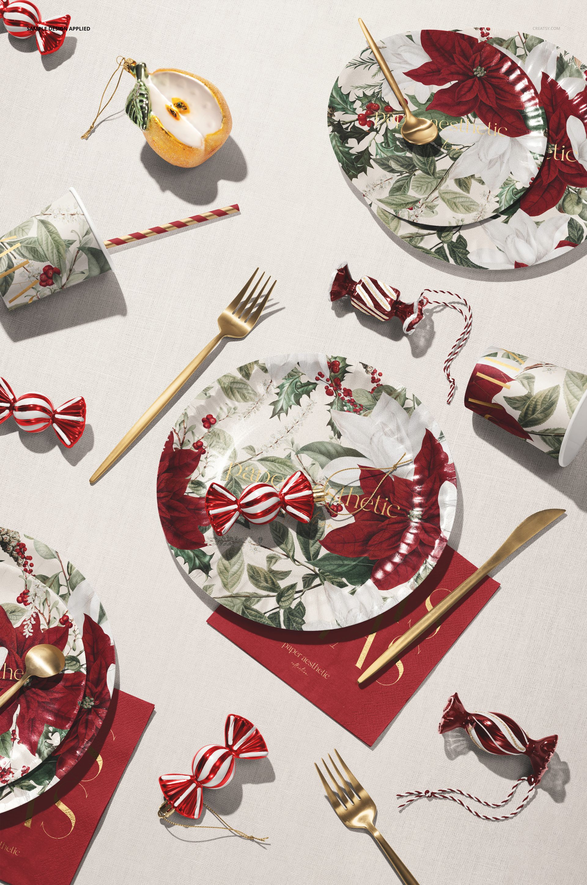 Disposable Christmas tableware mockup featuring plates, cups, and cutlery with red and green festive floral patterns.