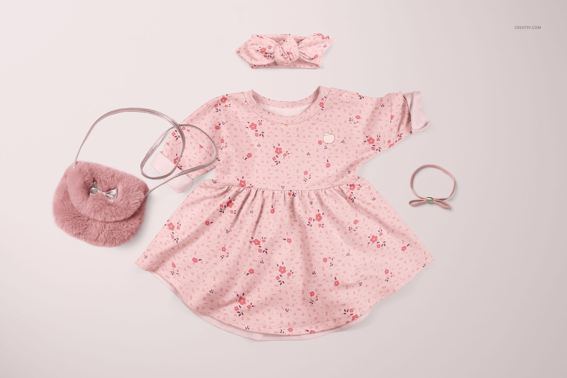 PSD mockup showing a pink floral baby dress and headband set, styled with a small purse and hair accessory on pale surface.