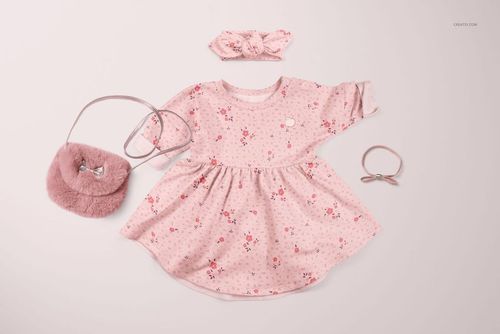 PSD mockup showing a pink floral baby dress and headband set, styled with a small purse and hair accessory on pale surface.