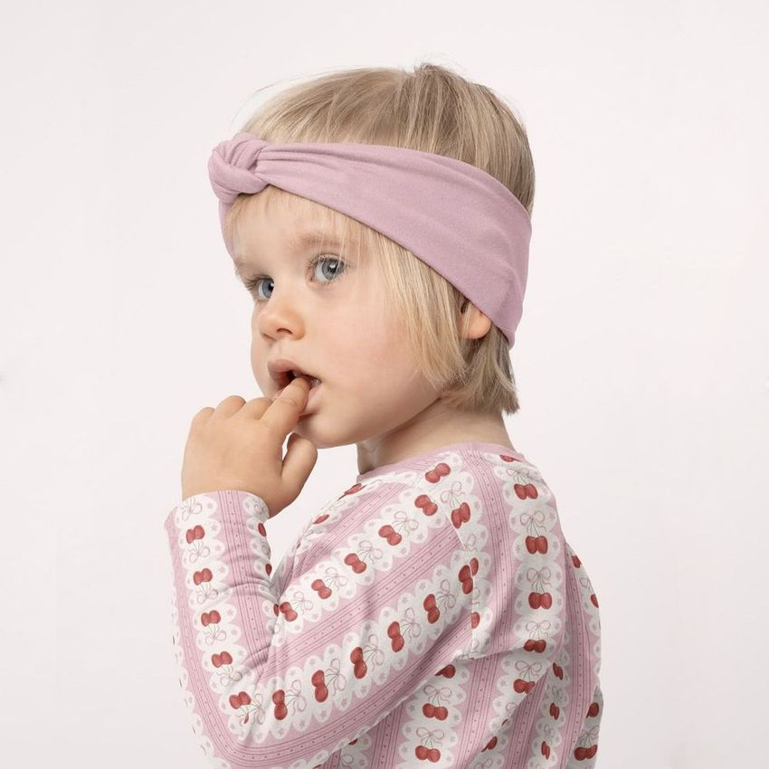 Kids adjustable headband mockup featuring a child wearing a light pink twist knot headband and cherry-patterned shirt.