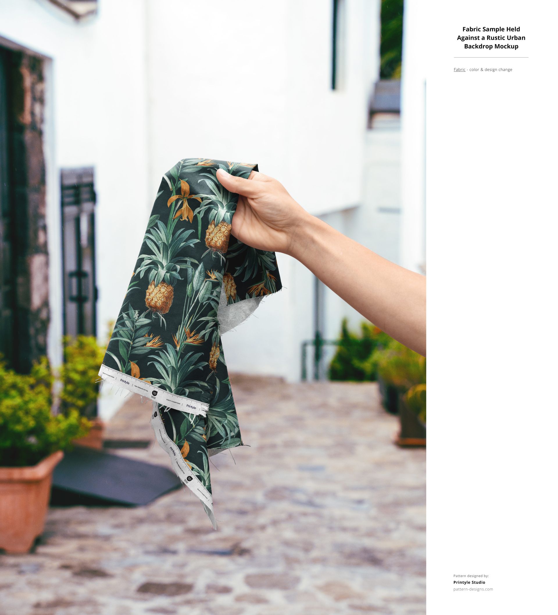 Fabric sample featuring a green and yellow tropical design, held up by hand in front of a rustic outdoor scene, PSD mockup.