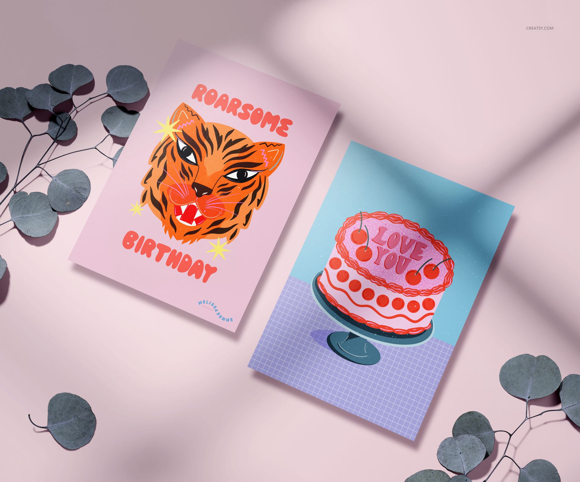 A5 greeting cards mockup featuring a tiger birthday card and a cake card, shown from a top view with leaf accents.