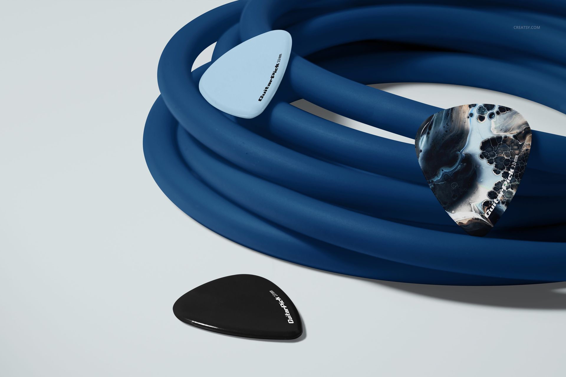 Assorted guitar picks, including black, blue, and marbled designs, placed beside a blue jack cable in a PSD mockup.
