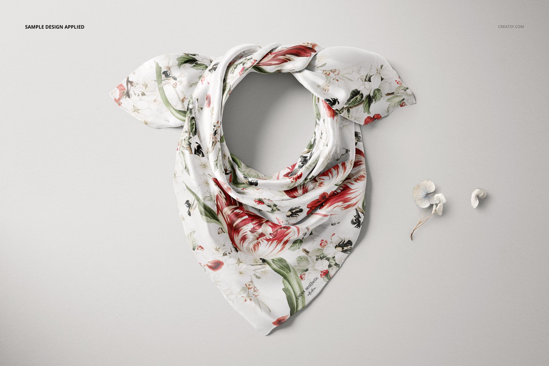 Silk scarf mockup displayed in a wrapped arrangement, featuring a floral pattern with red and green accents on white fabric.