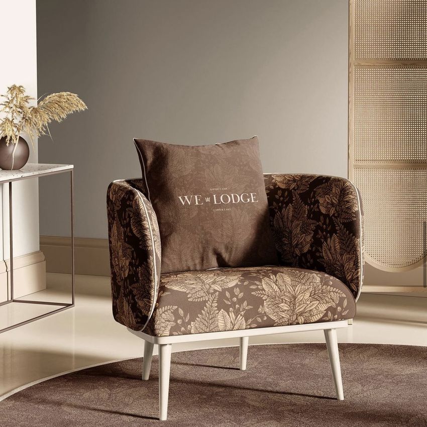 Armchair mockup in a sitting corner with brown botanical upholstery, a matching cushion with text, and neutral decor accents.