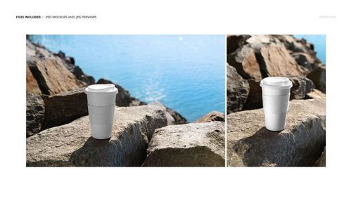 PSD mockup of a plain paper coffee cup with lid set on rocky shore, with water and sky in the background.