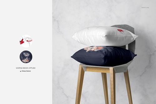 Pillow mockup showing a white and a navy pillow with floral designs, placed on a modern wooden chair in a minimalist room.