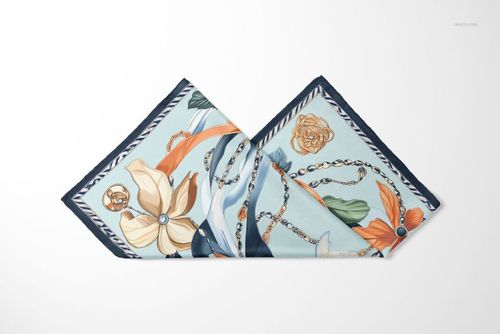 Folded silk scarf mockup featuring a mix of floral and chain motifs in blue, orange, and cream colors.