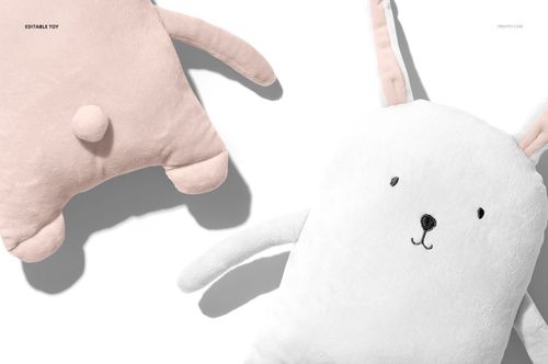 Close-up of baby wearable blanket mockup featuring a white bunny design and a pink plush toy, both on a light surface.