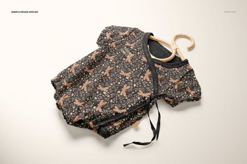 Top view of a muslin onesie mockup on a hanger, decorated with a black background and botanical print.