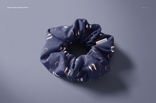 Cotton hair scrunchie mockup with a blue fabric featuring abstract white and orange patterns, shown on a gray background.