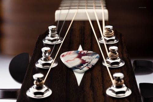 PSD mockup showing a detailed guitar headstock with chrome tuners and a multicolored pick positioned near the center.