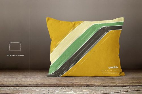 Small lumbar pillow mockup featuring a bold yellow base and diagonal green and black stripes, placed on rustic wood.