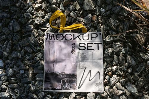 Outdoor tote bag mockup with bold yellow handles and printed design, displayed on textured stone ground.